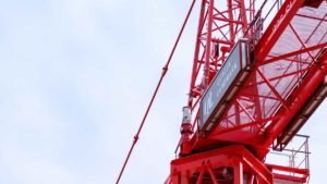 A red tower crane rising against a clear sky at an active residential construction site symbolizes the changing presale condo market and the strategic timing, research, and execution required to buy and secure favourable presale opportunities in the 2025–2026 real estate cycle.